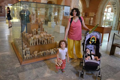 An image of K and the girls in front of an exhibit in the Chania Archaeological Museum with many bulls from a rural sanctuary