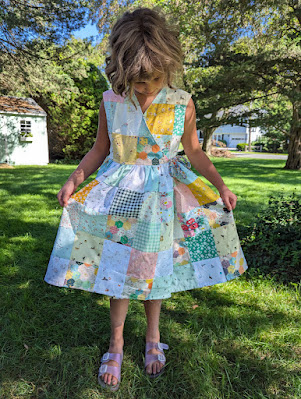 Sweet girl standing outside in grass, wearing a handmade reversible patchwork girl's wrap dress!