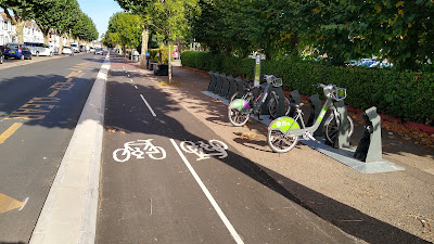 A two way cycle track with a cycle dock to the right with two cycles and empty spaces.