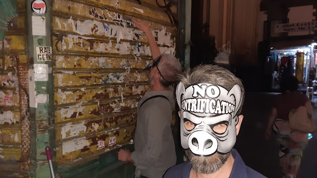 gli/le attivist@ in azione, uno in primo piano indossa la maschera di un maiale con scritto in fronte "no gentrification"