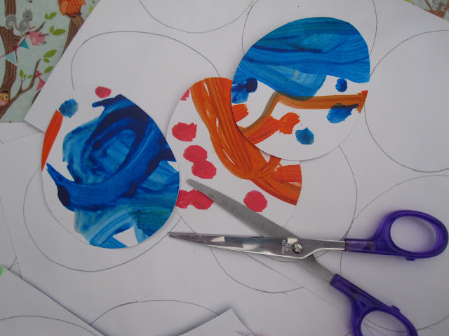 Multi-coloured egg shaped pieces of card next to a pair of scissors 