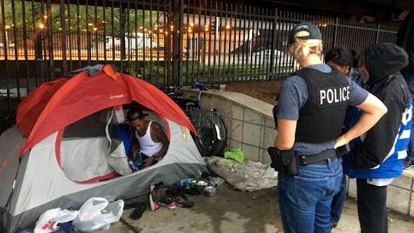 Two Chicago police officers arrived with representatives from the Department of Family and Social Services and Streets and Sanitation Workers to take Smith and Moore’s tent on a rainy day in late July. The officers told WBEZ that tents are not allowed in the central business district. Odette Yousef/WBEZ