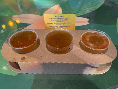 A flight of three beers in a brown cardboard carrier with tasters of Orange Twist Imperial Ale, Lemon Drop Shandy, and Tangerine Express Hazy IPA