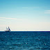 Ship sailing over the horizon of the blue sea