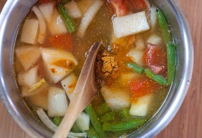 Adding sambar powder to vegetables and lentils before they are simmered