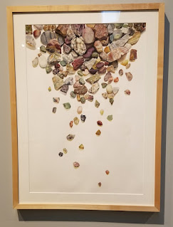 A framed painting of wet river rocks entitled “Truth or Consequences” by Meghan Flynn, egg tempera on watercolor paper.