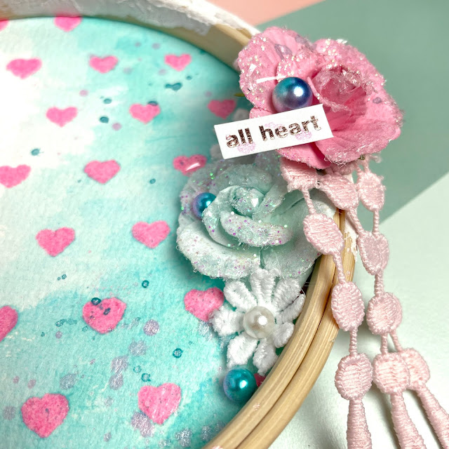 Mixed Media Altered Embroidery Hoop made with  Prima Marketing paper flowers and chipboard stickers; Scrapbook.com stencil, stickers and Pops of Color, Tim Holtz Distress Ink in Salvaged Patina and Distress Glaze in Kitsch Flamingo; and Reneabouquets Glass Glitter (ocean and pale pink), Beautiful Beads in Mermaid Tails, embroidered lace and a Tiny Treasures Dragonfly.
