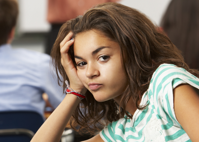 Middle school female student is bored when teacher reads through the syllabus on the first day of school.