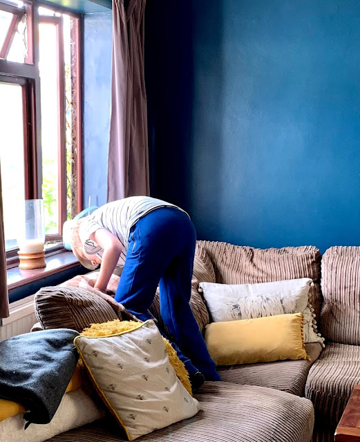 boy looking behind sofa at squirrel