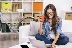 A smiling woman with her legs folded, typing on her computer, and asking ,are distance learning degrees respected?