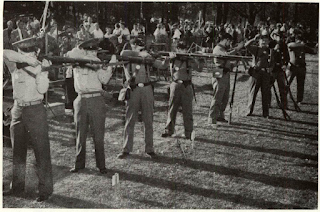 Modern skeptics are convinced of Minie ball’s devastation when exhibitions of shooting between military men armed with Garands conclude with victory to North South Skirmish Association members armed with Civil War rifle muskets. Target, 2x4 stake, is cut in half by bullets, recalls forests chopped off breast high by rifle fire in Civil War. Scene pictured is from annual fete at Ford museum’s Greenfield Village, Dearborn, Mich.