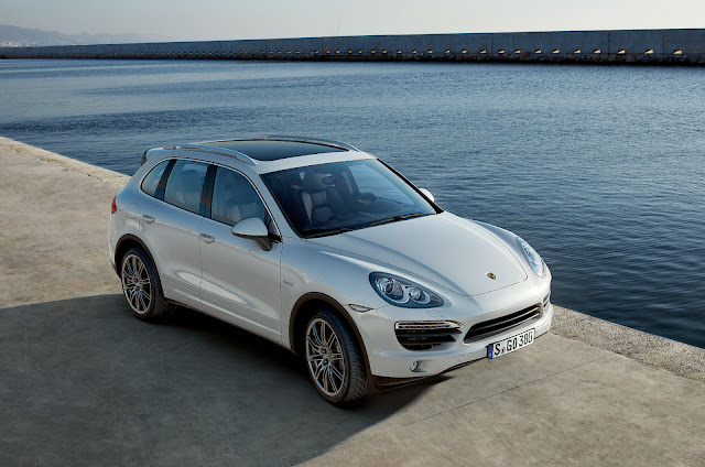 Front 3/4 view from above of white 2011 Porsche Cayenne Hybrid parked next to water