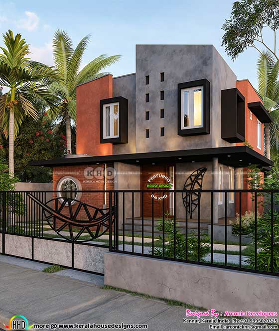 A view of the modern home's exterior, featuring a dark color palette with grey, brown, and orange accents, highlighted by a stunning metal leaf design and a red brick section with a round glass window.