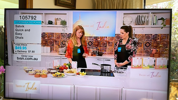 A fan's at-home snapshot of Rada on live TV, showcasing Satvik Foods' products on the shopping channel TVSN. The products include healthy and delicious options such as spiced dhals, rice, and organic quinoa with unique Ayurvedic spice blends. Rada's enthusiasm and expertise are on full display as she introduces viewers to the company's offerings