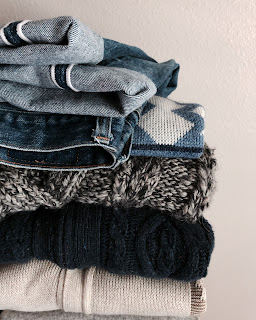 A stack of vintage clothing of jeans and sweaters.