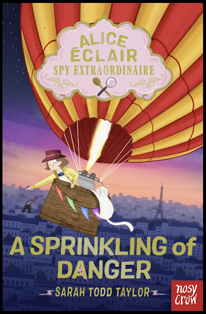 Large book cover. Alice Eclair leans over the edge of the hot air balloon basket, pointing to Paris below. The sky is filled with stars, and there is a blue, purple and light umber horizon picking out the buildings and eiffel tower below.  Casper, the white cat, hangs on for dear to the outside of the basket. The balloon is of verticle stripes alternating in red and yellow. The basket has multicoloured bunting on the outside. 'Alice Eclair Spy Extraordinaire', appears in an ornate cake-pink panel edged in gold at the top of the page. Within the panel are a small crossed wooden spoon and magnifying glass. 'A sprinkling of Danger' and the author's name appear in dull gold at the bottom of the cover. The burner in the centre of the balloon is lit and a bright white and yellow flame roars up into the balloon body.