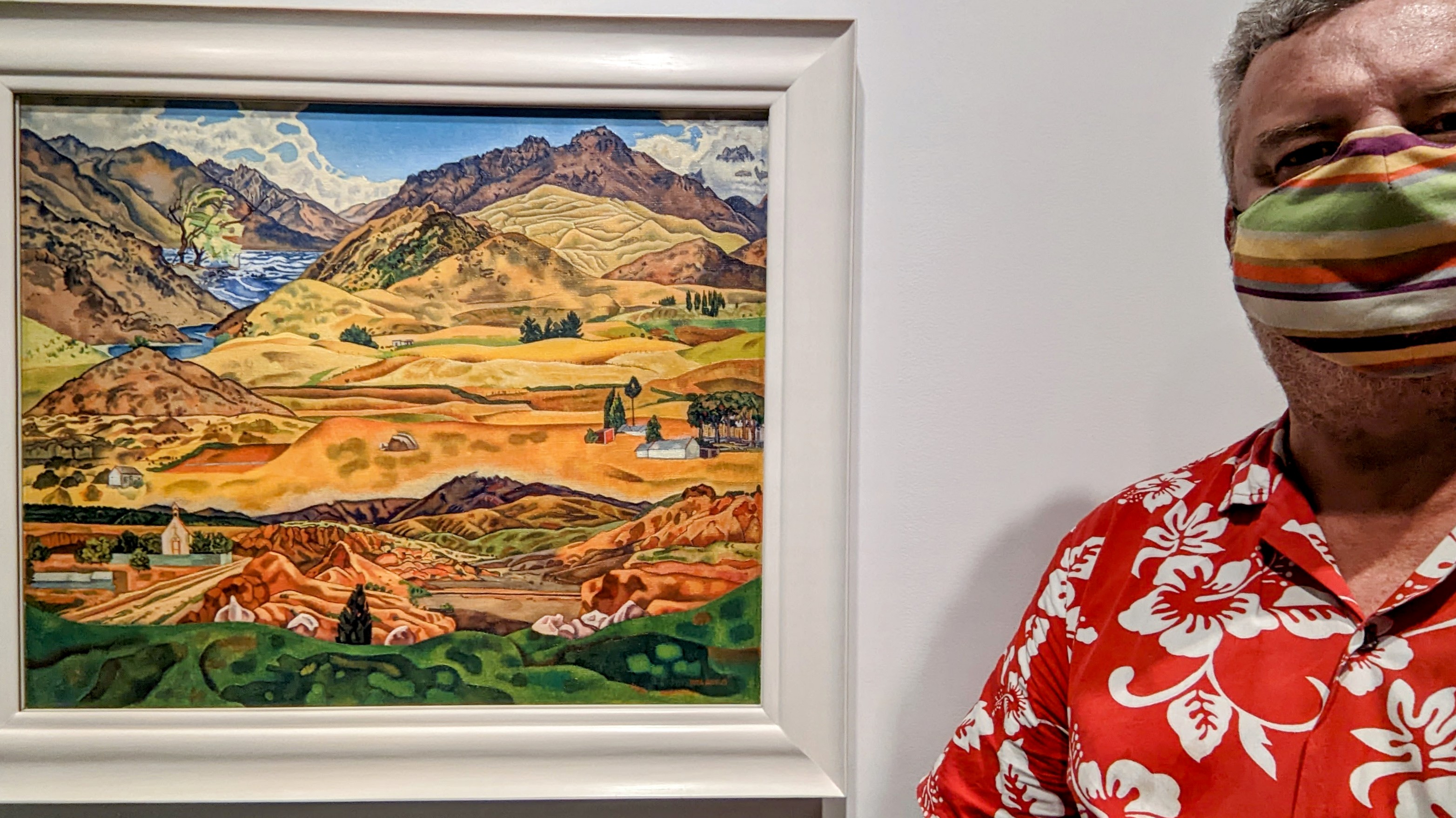 COVID masked Mike Riversdale stood near the Rita Angus painting 'Central Otago'