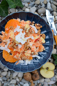 Rohkost aus Topinambur, Karotten, Mandarinen, Birnen und Kokos auf einem blauen Teller.