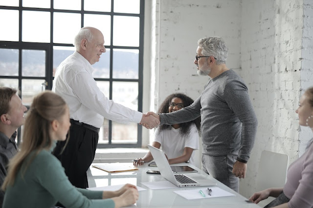 Boss appreciates work and shakes hand with team member.