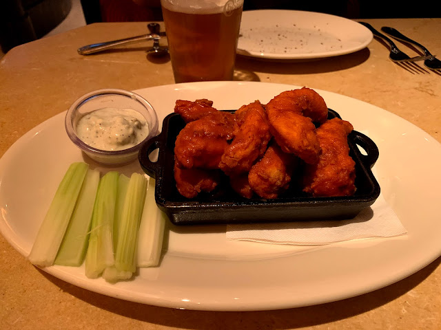 White plate with buffalo chicken strips, celery sticks and blue cheese sauce