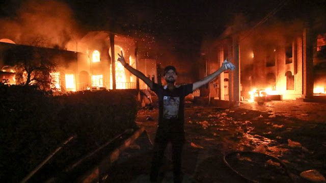 An Iraqi protester stands flashing the victory gesture outside the burning headquarters of the Iranian Consulate in Basra on Sept. 7.