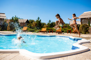 Niños se lanzan a una piscina en un día soleado.