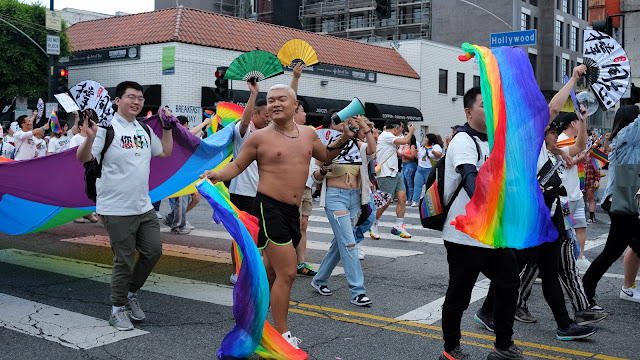 Young men celebrate pride.  Lots of rainbow flags and smiles and movement.