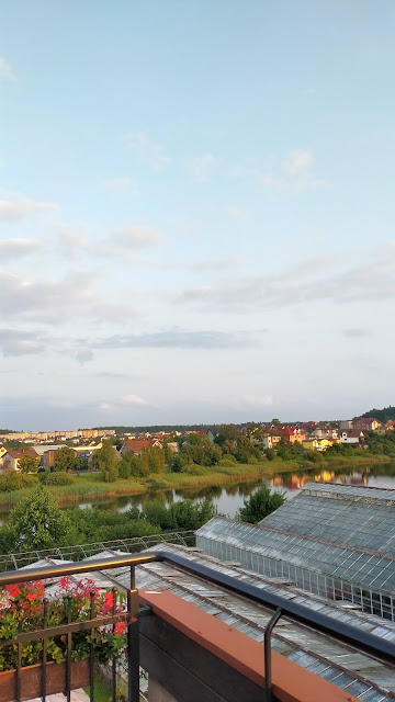 widok z okna na pobliskie zabudowania przy zachodzie słońca