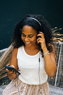 young black woman listenign to a podcast with headphones.
