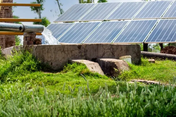 Farmland with solar panels and wind turbines generating renewable energy under a clear sky.