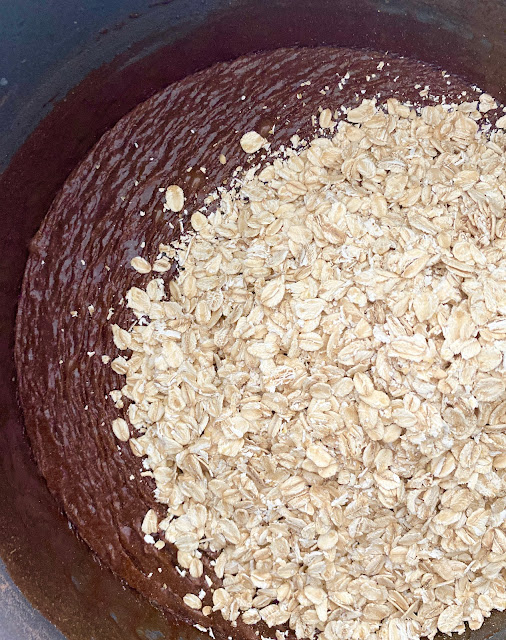 A stainless steel bowl of melted chocolate and oatmeal.