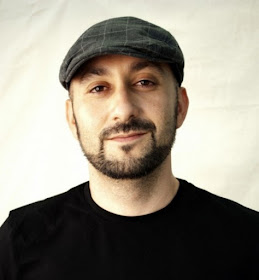 Head shot of poet Craig Santos Perez in a cap