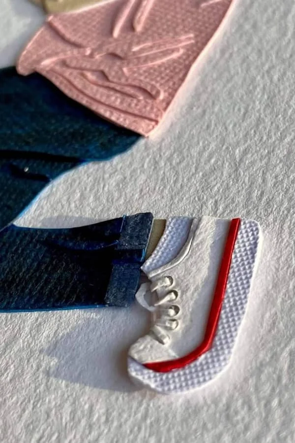 detail of paper art figure wearing blue jeans and white sneaker