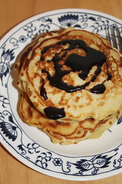 Stack of oatmeal pancakes topped with butter molasses sauce.