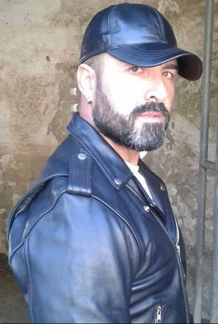Sexy bearded Leathermen bring a black leather biker jacket and hat
