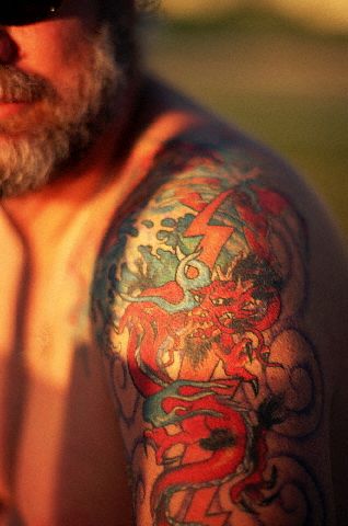 Red dragon and thunder tattoo on bearded male's upper arm.