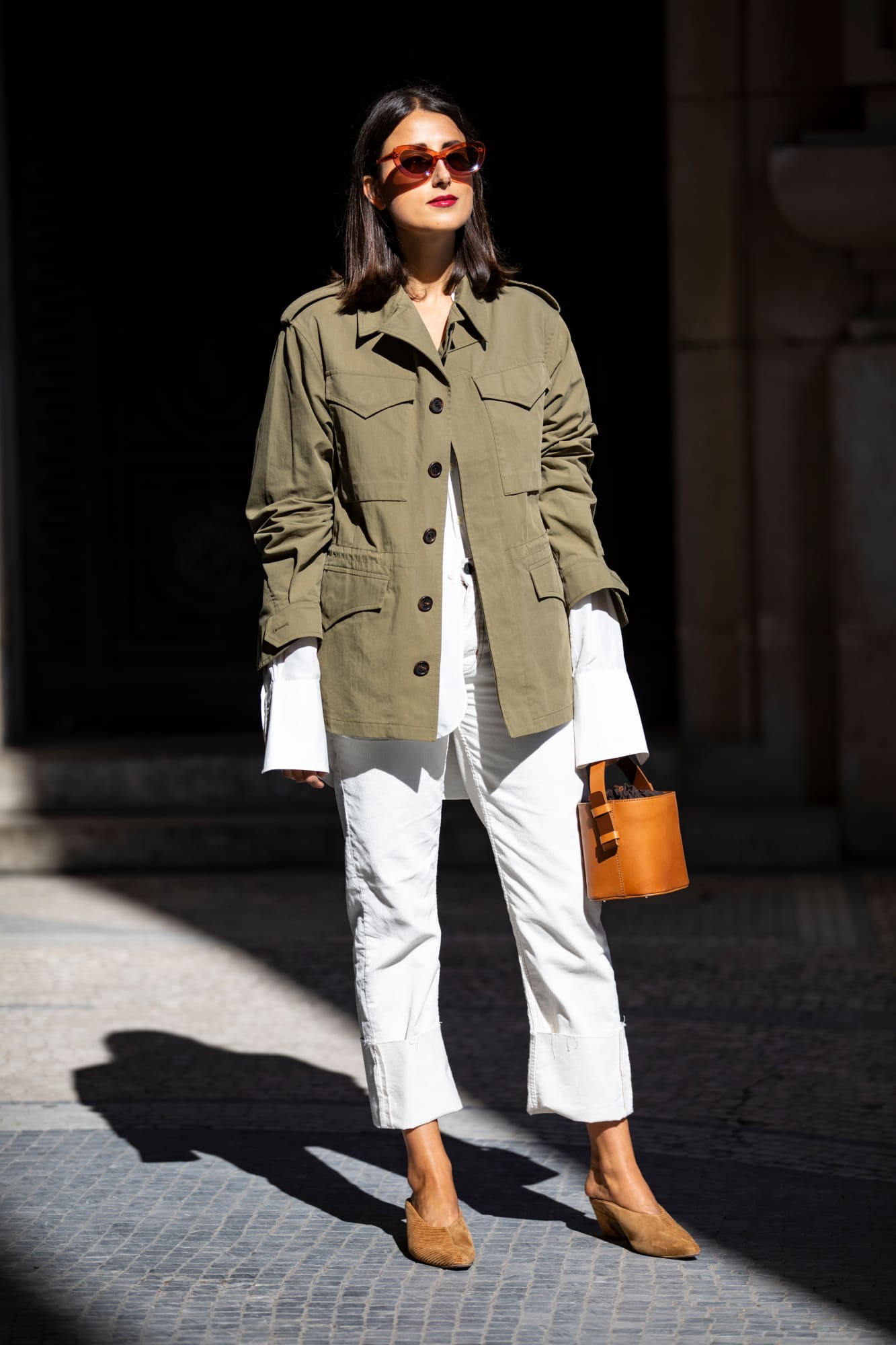 Spring outfit idea and wardrobe staples — green utility jacket, oval sunglasses, white jeans, mule heels