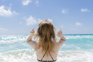 back of woman's head as she feels her hair at beach.jpeg