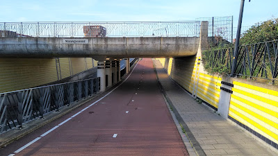 A cycle track going under a railway with a road to the left lower down.