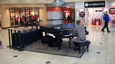 A piano set up in the middle of the airport, with a guy playing very lovely songs for the people walking by.