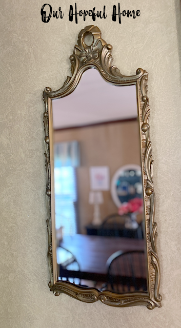 gold plastic thrift store mirror hanging on wall