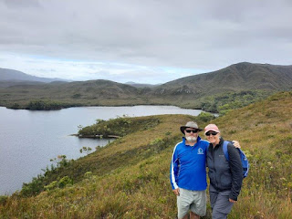 Couple on hill overlooking a bay in the Tasmanian South West wilderness