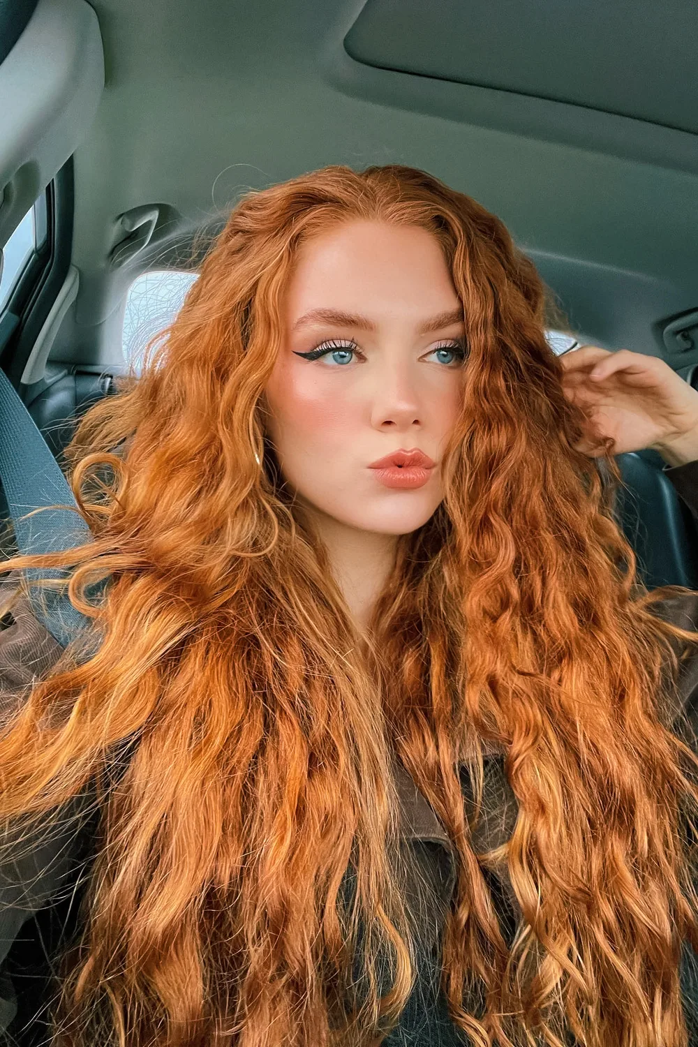 selfie of a beautiful, young woman with long and curly ginger hair