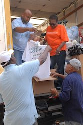 Rev. Randy Vaughn, left foreground, of Mount Sinai Missionary Baptist Church and volunteers from the church unload supplies from delivered by World Vision.