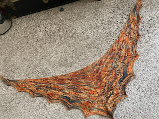 a shawl shaped like the outstretched wings of a dragon in orange/yellow/black dyed yarn