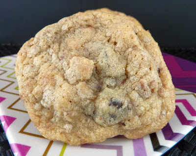 Chocolate Chip Cookie, made with Espresso Chocolate Chips, toffee chips, and pecans. Photographed on a plate with pink and purple zigzags