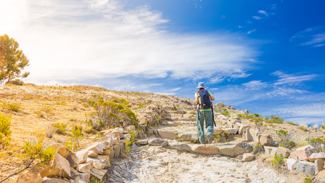 a solo hiker heading up the hill under a bright sun