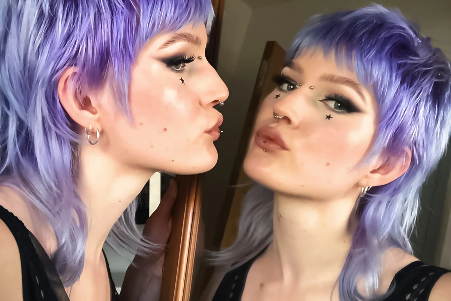 woman with dyed edgy mullet haircut is posing in front of a big mirror