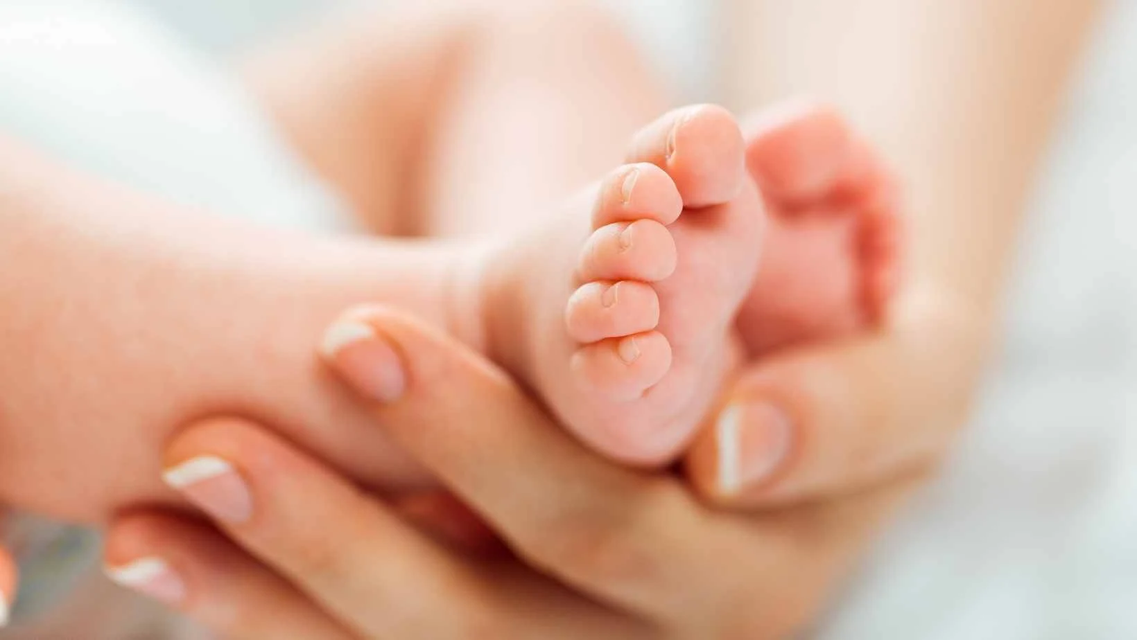 Canva stock image for a new baby showing a babies feet in a woman's hands