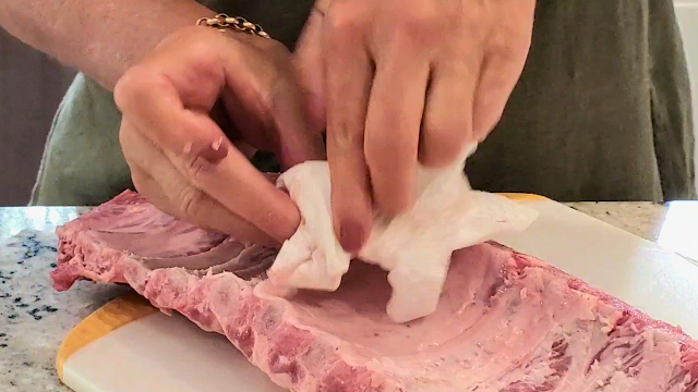 Using a paper towel to remove the membrane from a rack of ribs.